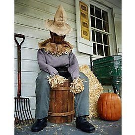 Handmade scarecrow sitting on a haystack with a friendly smile