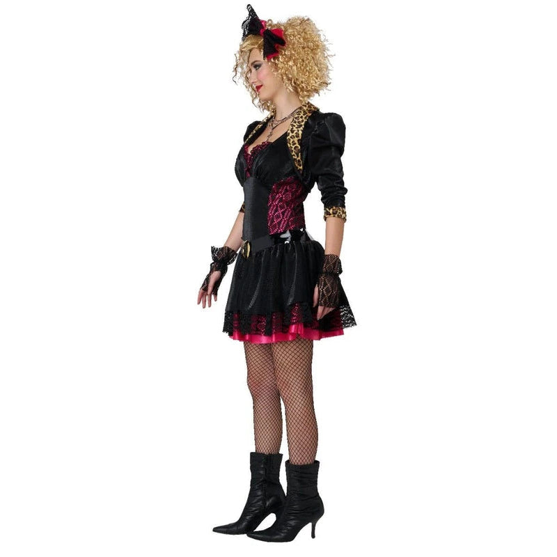 A woman modeling a black and pink gothic costume with a short dress, fishnet stockings, black pointed boots, and a blonde wig with a black horn accessory, set against a plain white background.