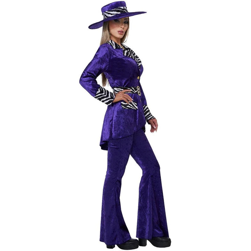A woman modeling a purple velvet two-piece costume set with black and white zebra-patterned trim, a matching wide-brim hat, and black shoes, photographed against a plain white background.