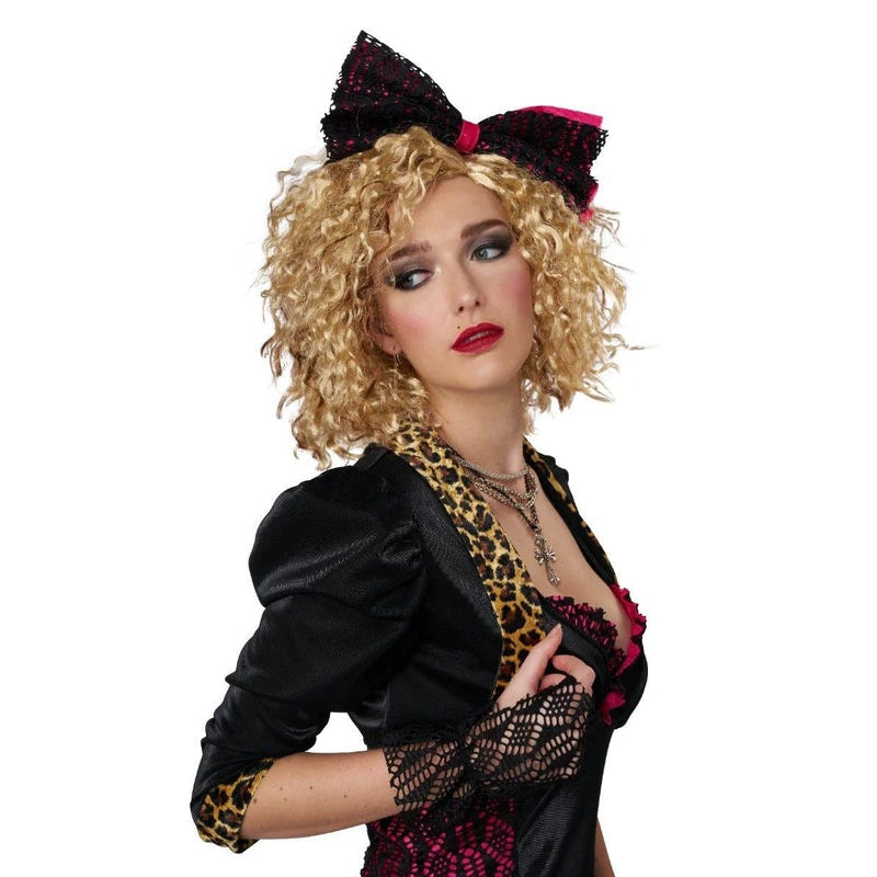 A woman modeling a black and gold leopard-print costume with a large black sequined bow headpiece, curly blonde wig, and red lipstick, set against a plain white background.