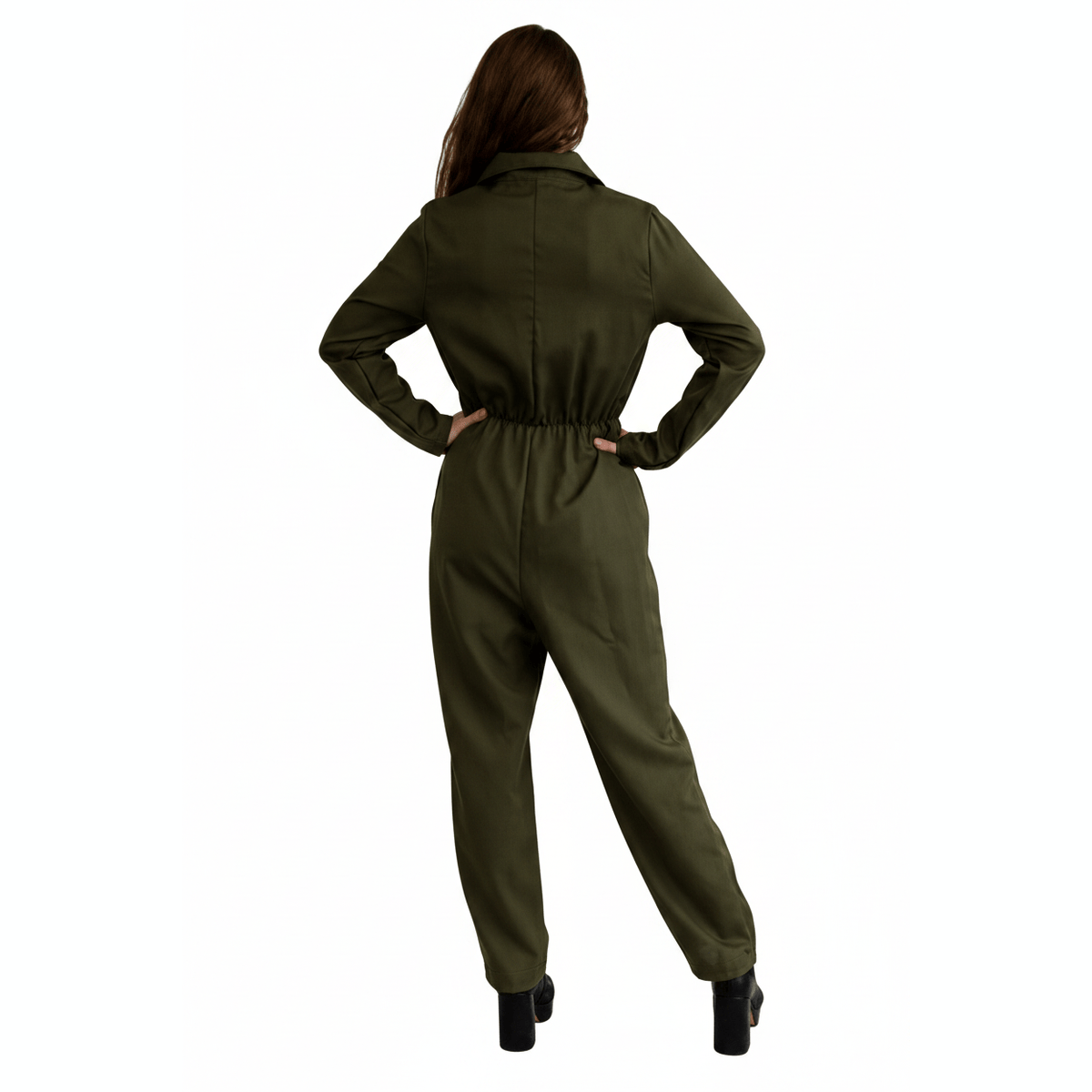 A woman shown from the back wearing an olive green one-piece jumpsuit, with her hands on her hips, set against a plain white background.