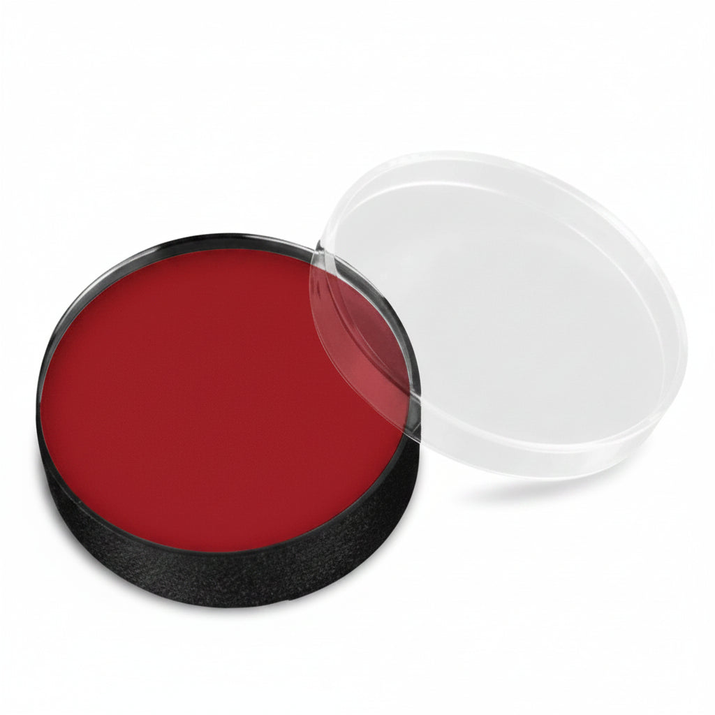 A round makeup or cream product pan filled with deep red cream, shown open with a clear plastic lid resting beside it on a white background.