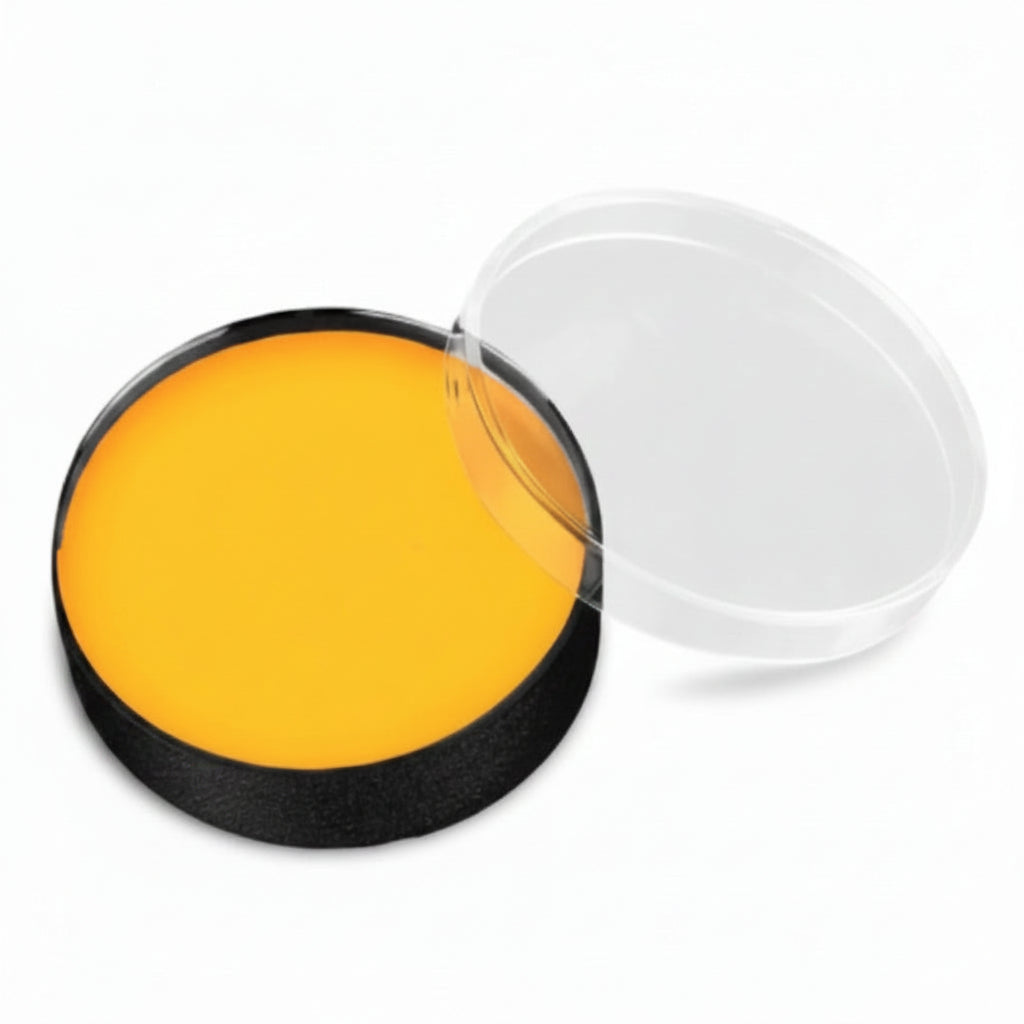 A circular black makeup pan filled with bright yellow cream or powder, shown open with a clear plastic lid resting beside it on a white background.