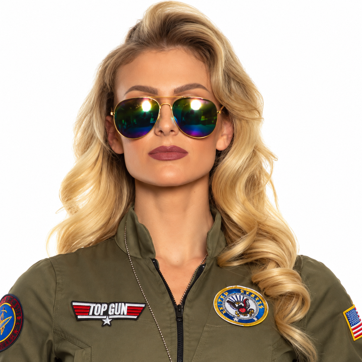A blonde woman wearing aviator sunglasses with iridescent green-blue reflective lenses and an olive green flight jacket with 'TOP GUN' and military-style patches, photographed against a plain white background.