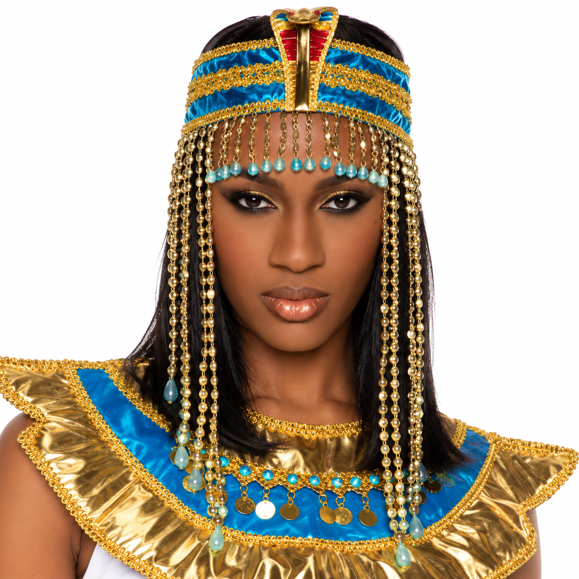 A woman wearing an Egyptian goddess costume headpiece and collar with gold and blue metallic details, turquoise beads, and dangling gold chains, photographed against a plain white background.