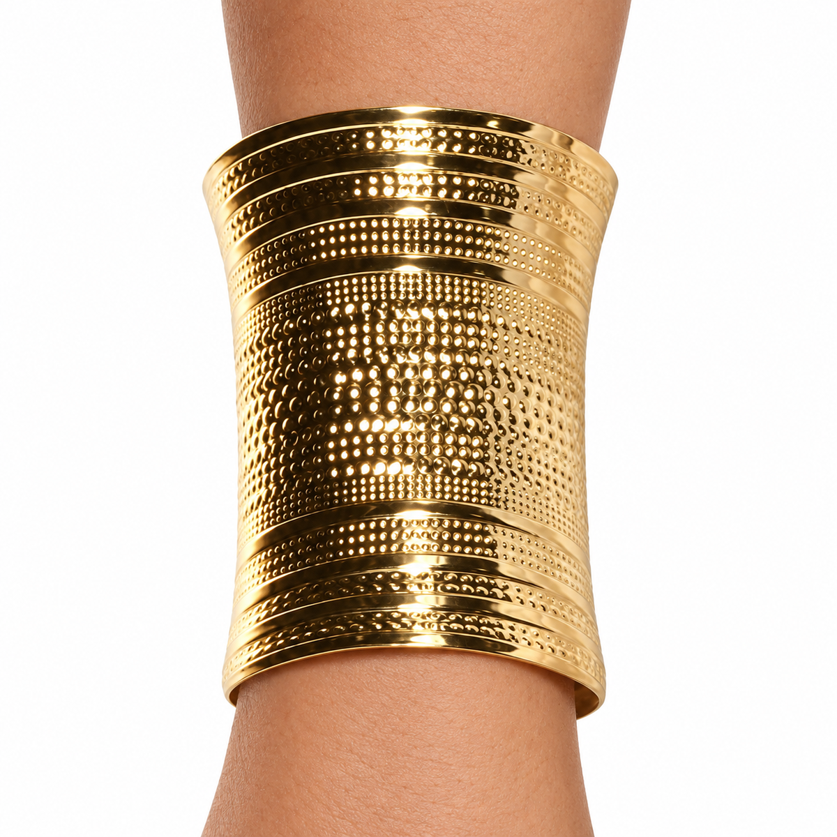 A wide, textured gold cuff bracelet worn on a person's wrist, shown against a plain white background.