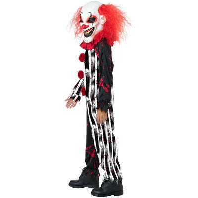 A child modeling a scary clown costume against a plain white background. The costume includes a white and red clown mask with a wide grin, bright red hair, a black and white striped jumpsuit with red blood-like splatters, and black shoes.