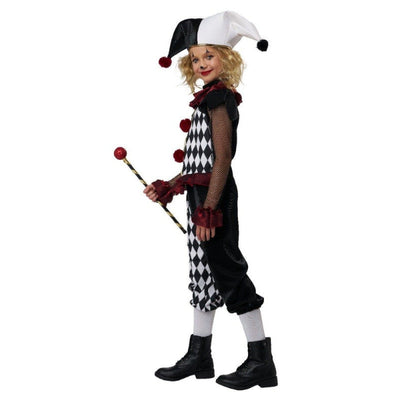 A child modeling a black and white harlequin jester costume, holding a small jester staff, against a plain white background.