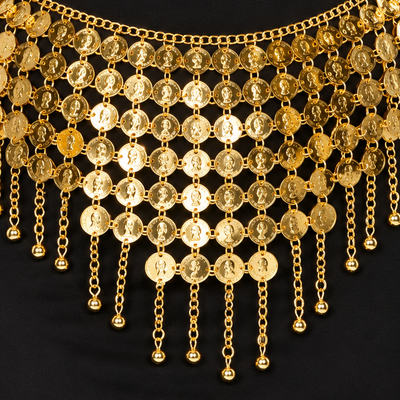 A gold coin belly dance belt with dangling chains and coin-shaped discs, worn over a black dress on a model.