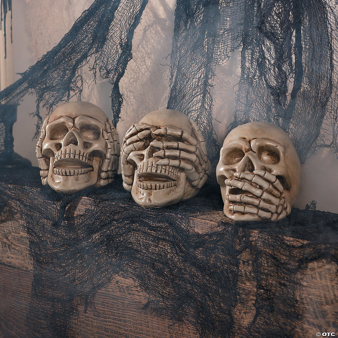 Three skull figurines in resin, each covering their ears, eyes, and mouth with their hands, representing 'Hear no Evil, See no Evil, Speak no Evil' concept 