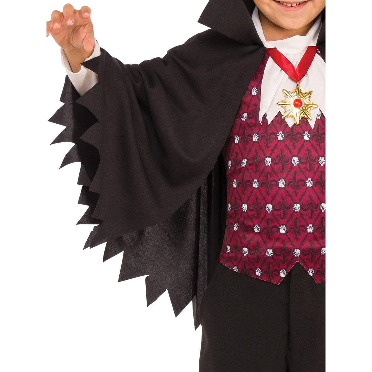 Child wearing a costume with a black cape and red vest with white patterns on a white background