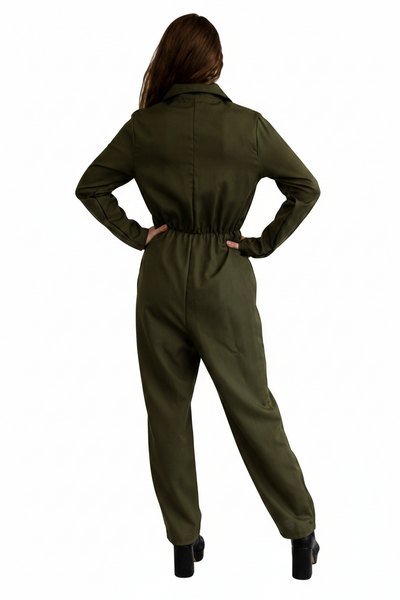 A woman shown from the back wearing an olive green one-piece jumpsuit, with her hands on her hips, set against a plain white background.