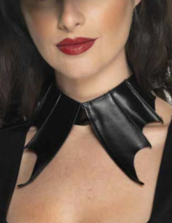 A close-up of a woman wearing a black faux-leather gothic collar with pointed bat-like wings, styled with red lipstick and a black top.