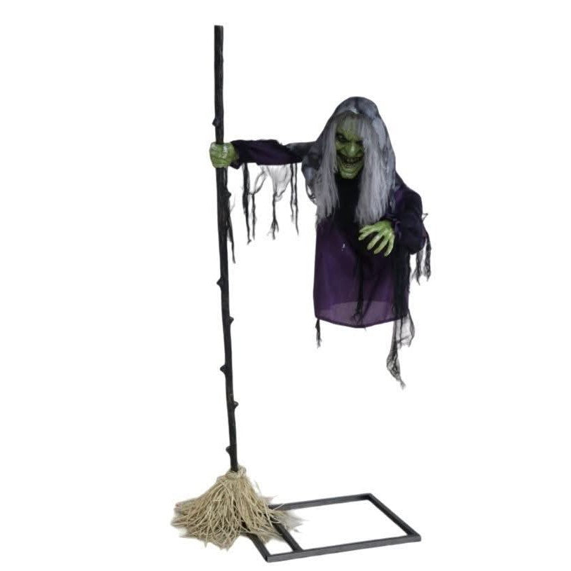 Life-size witch animatronic with green face, grey hair, purple tattered robe and gnarled broomstick on stable base frame