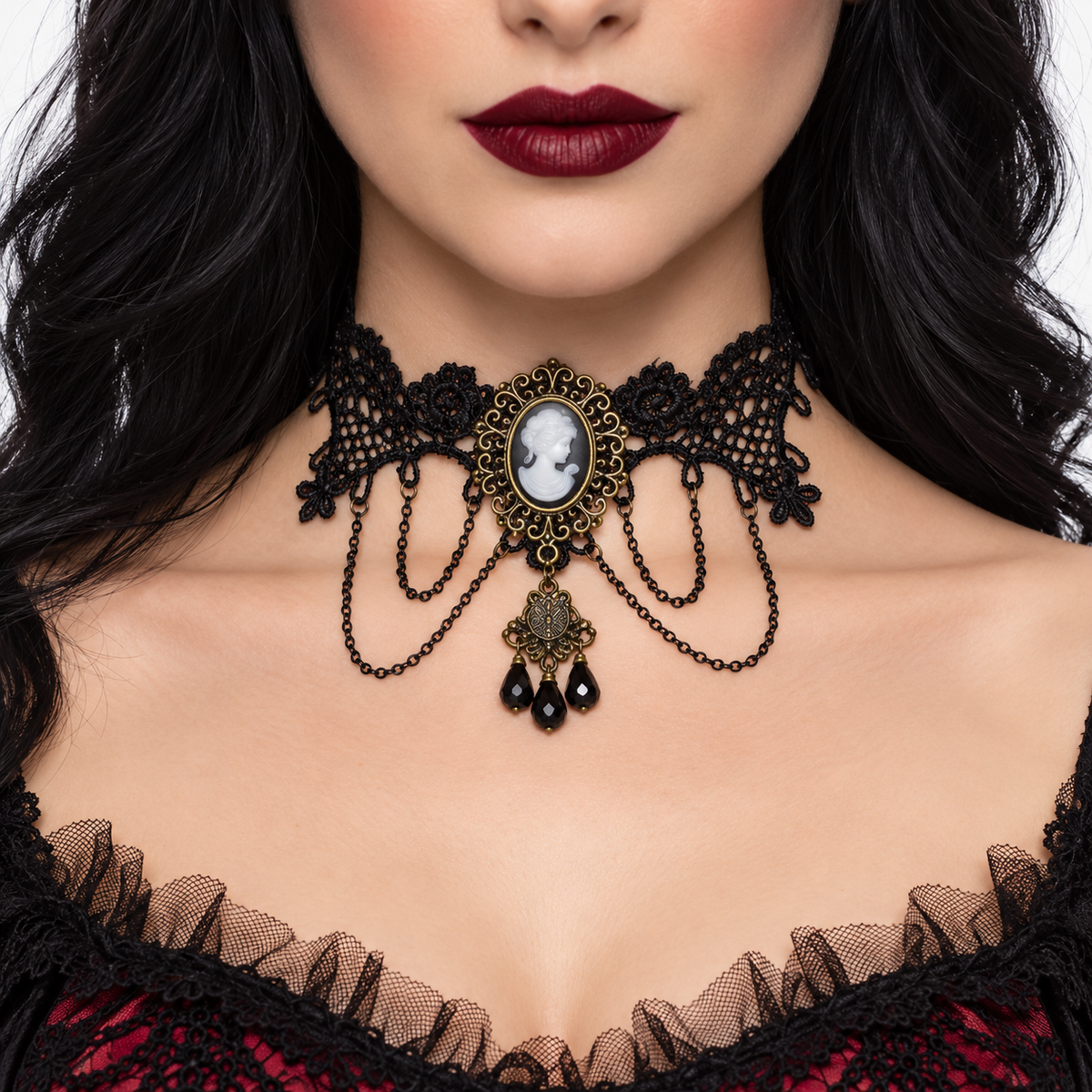 A close-up of a model wearing a gothic-style black lace choker necklace with antique bronze metal detailing, a cameo-style oval centerpiece, and dangling black teardrop beads.