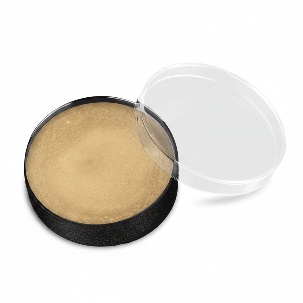A round makeup compact with a black base containing a light beige pressed powder, shown with its clear plastic lid resting beside it on a white background.