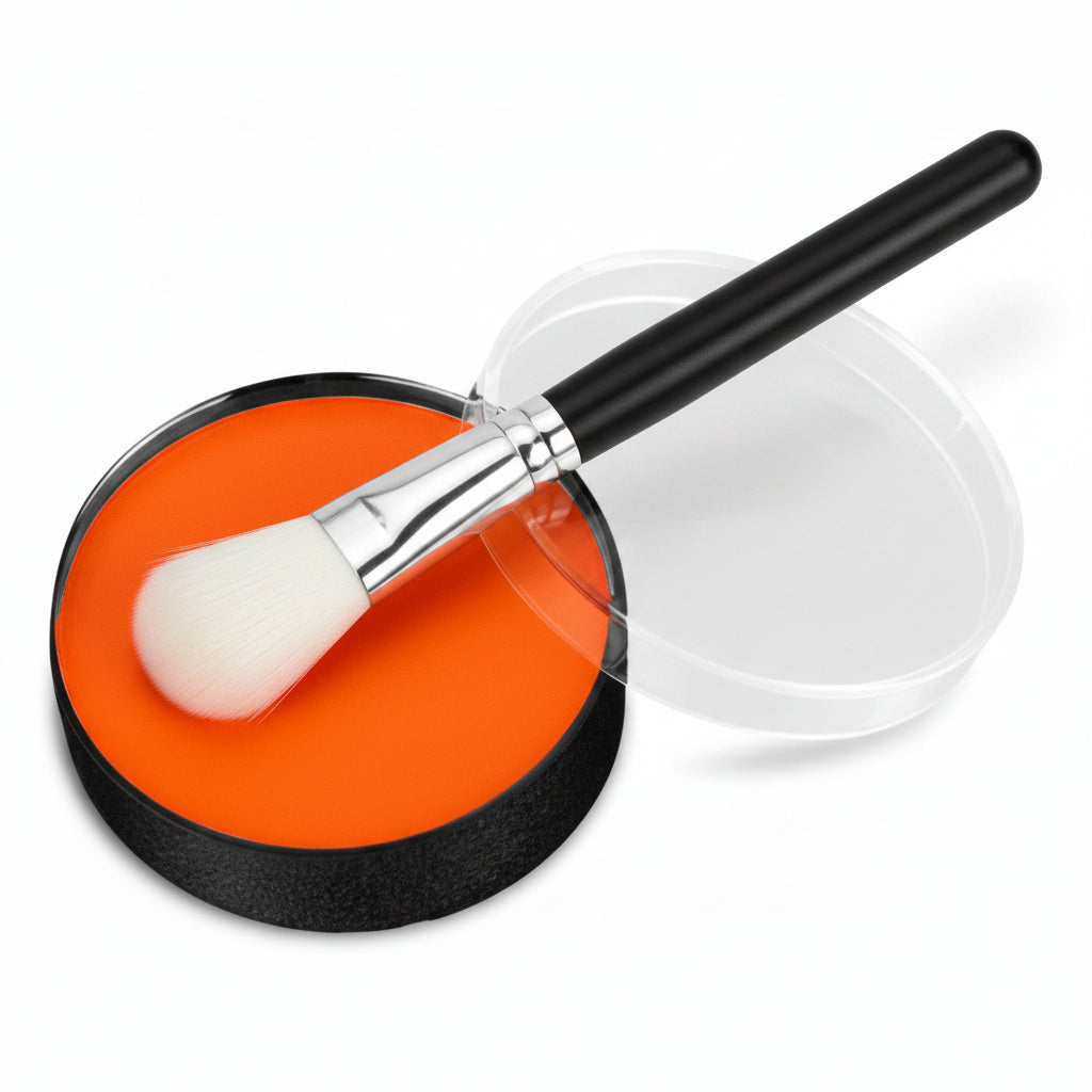 A round makeup compact showing a vibrant orange pressed powder, with its clear plastic lid resting beside it on a clean white background.