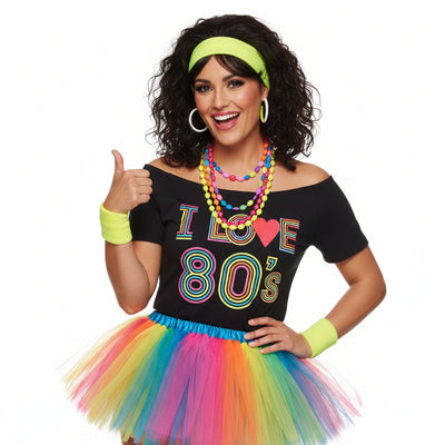 A woman modeling a 1980s retro costume consisting of a black t-shirt with 'I Love 1985' in colorful text, a yellow headband and wristbands, gold necklaces, and a rainbow tutu skirt.