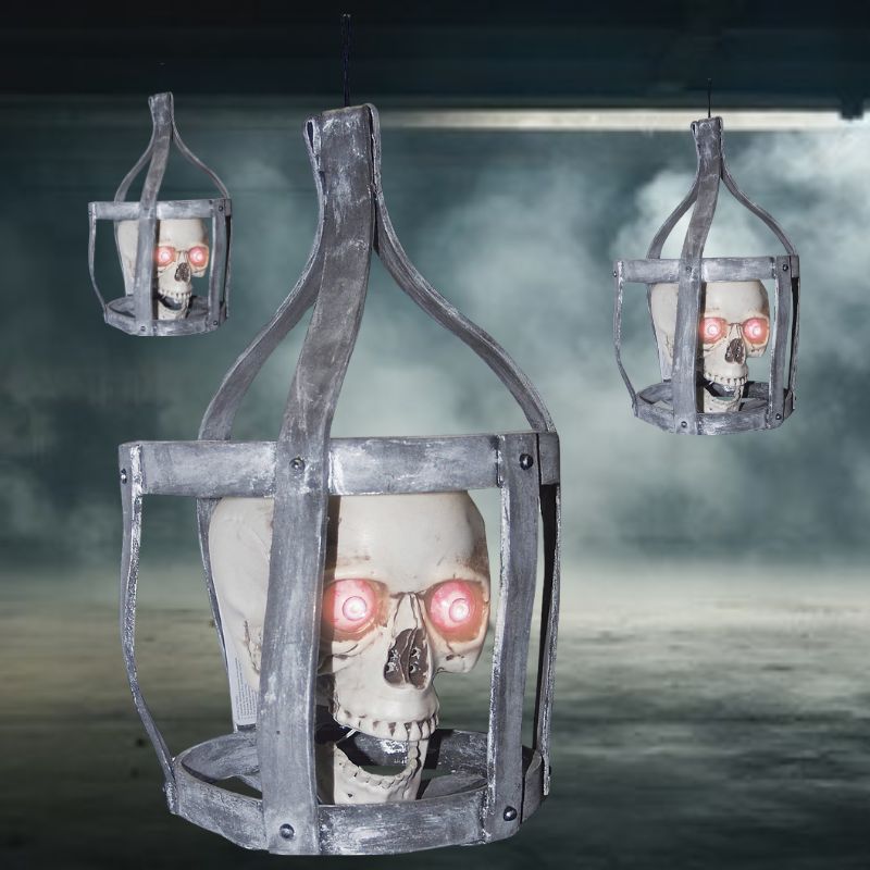 Alt text: Spooky Halloween decoration of a lifelike talking skull in a rustic iron cage