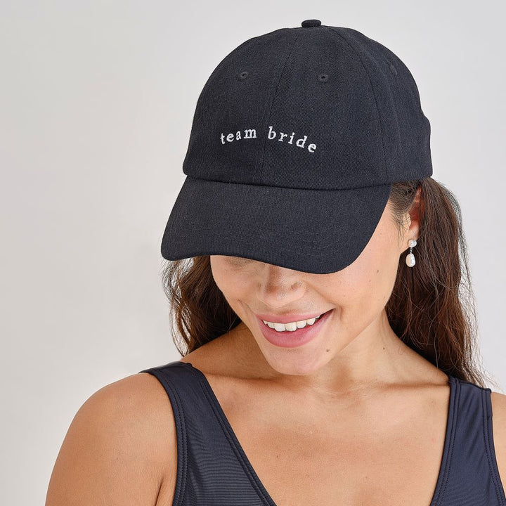 Group of women wearing matching Team Bride Black Caps at bachelorette party 