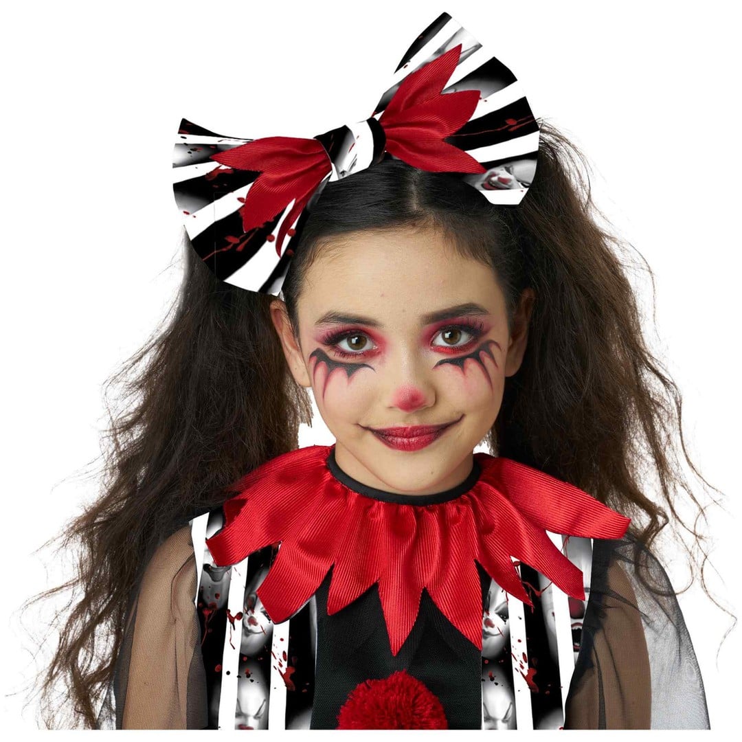 A child model wearing a creepy clown costume accessory set, featuring a large black and white striped bow with red accents in her hair and a matching red ruffled collar, against a plain white background.